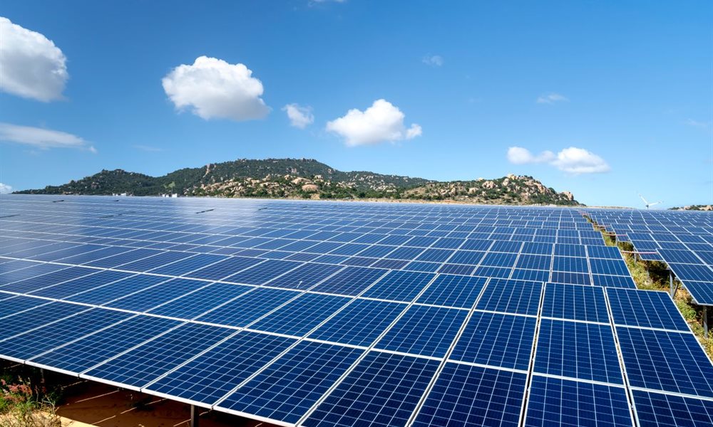 夏の青空の下に広がる太陽光発電所とパネル周辺の緑地